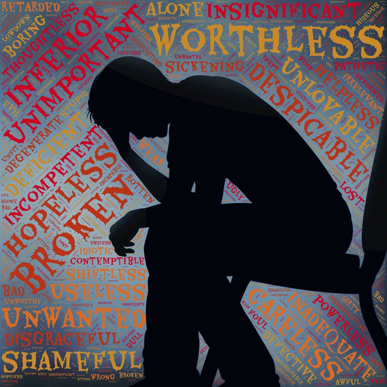 Silhouette d'une personne recroquevillée entourée de mots négatifs comme Broken, Worthless et Hopeless